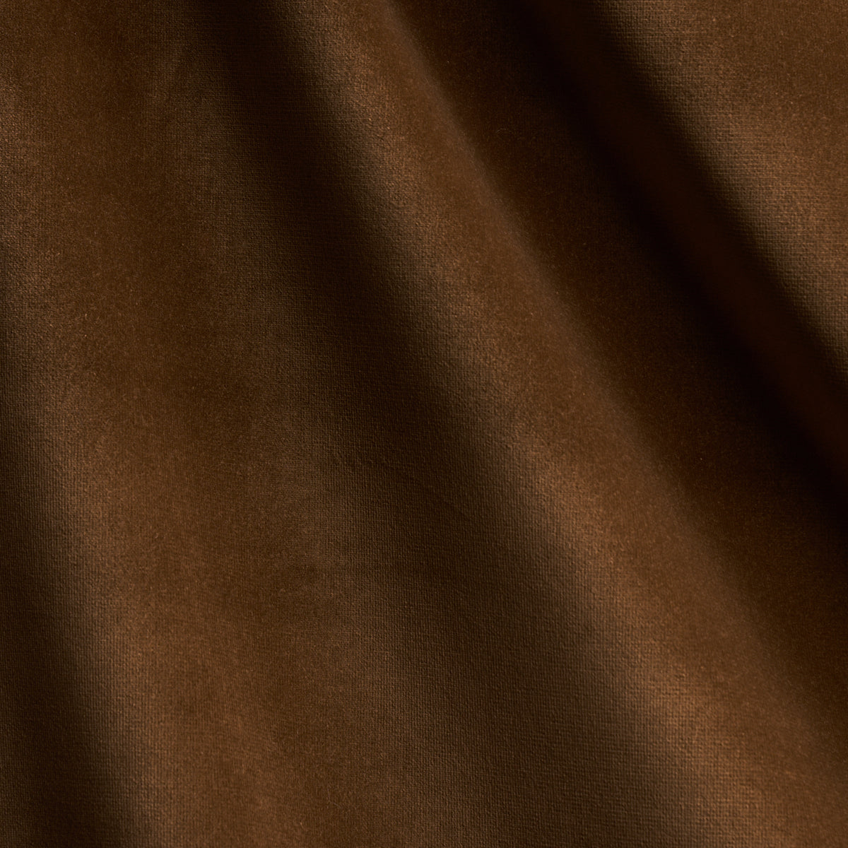 Close-up of brown velvet fabric with soft texture and diagonal folds.