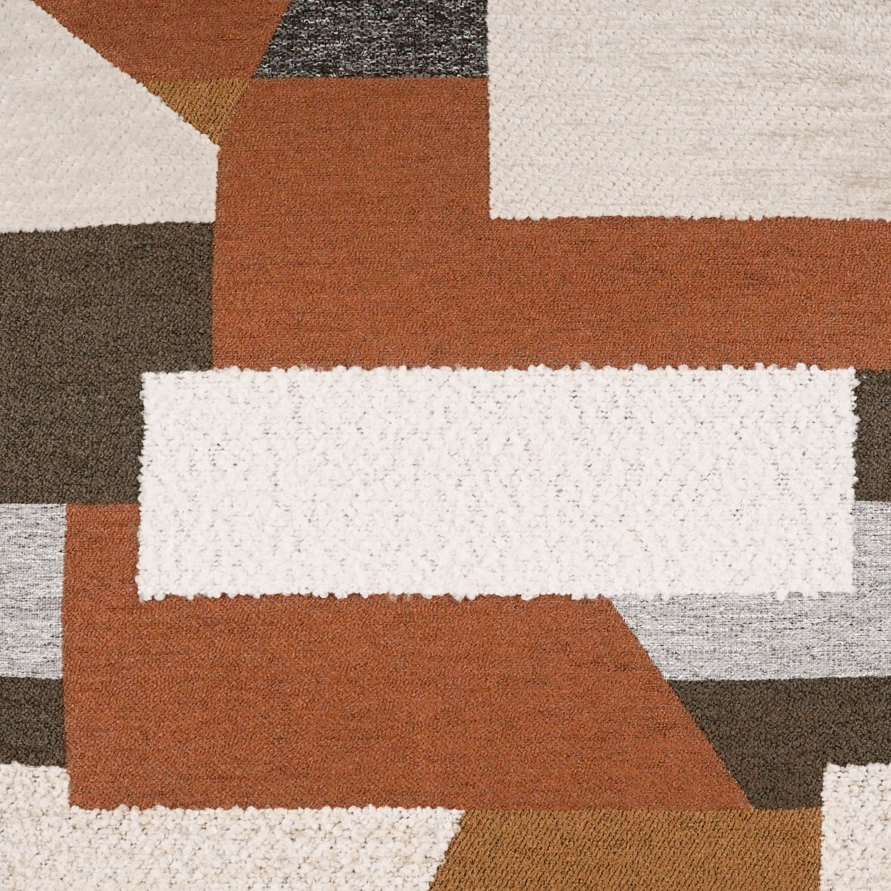 Geometric rug in rust orange, beige, cream and brown with plush pile and rectangular block pattern.