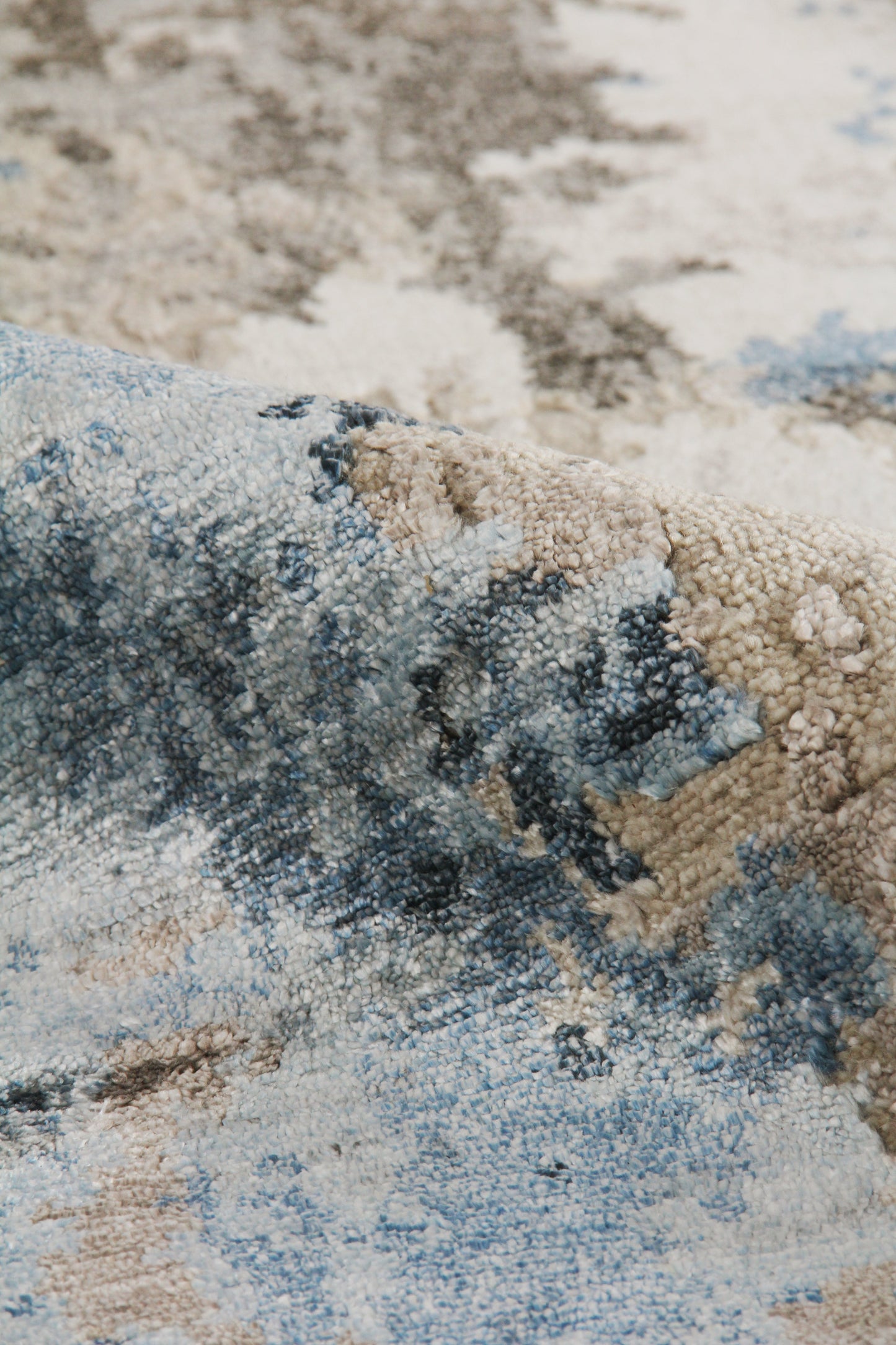 Abstract blue, beige and ivory area rug with plush looped pile and textured pattern.
