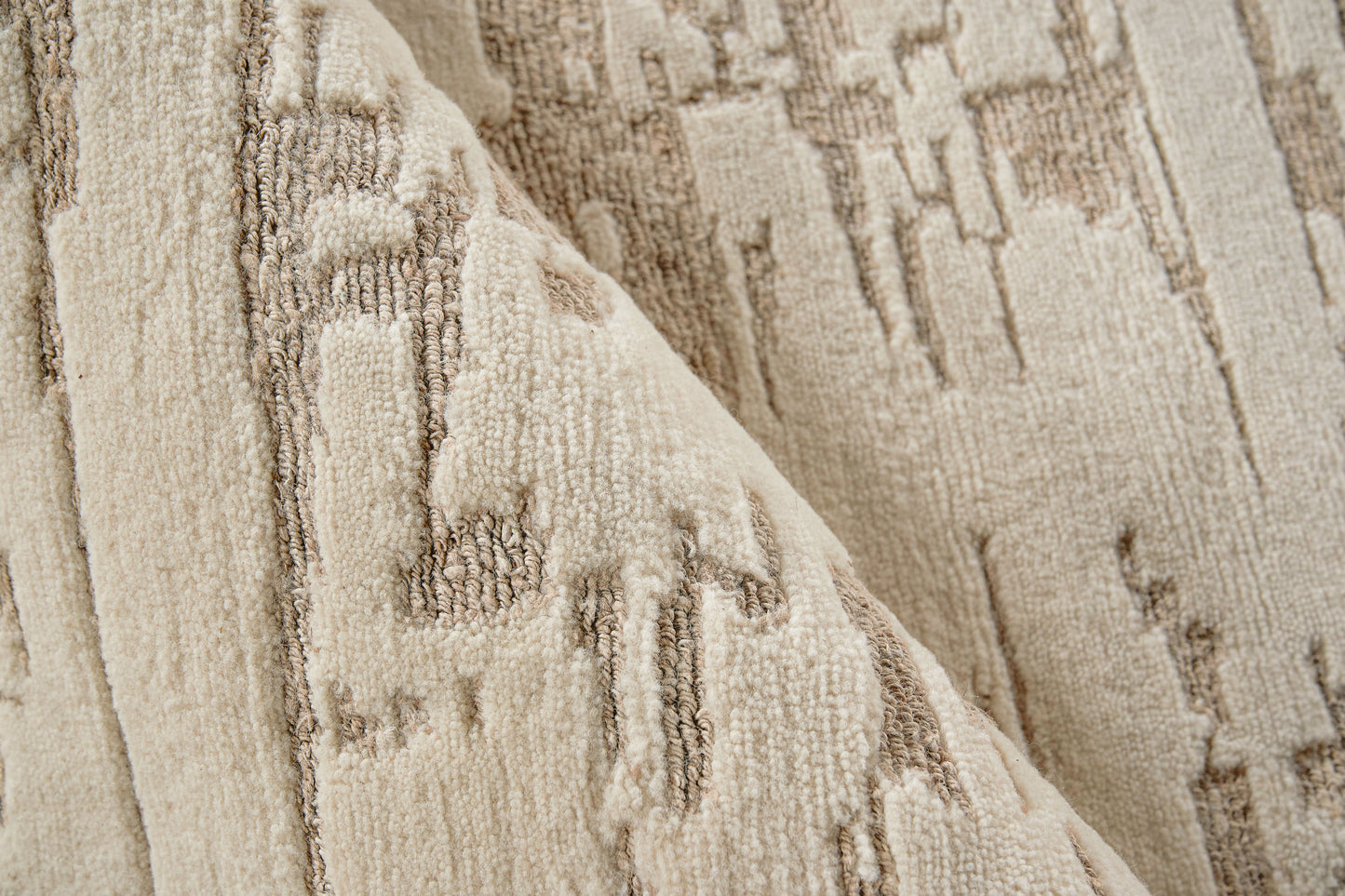 Beige textured woven rug with subtle brown geometric pattern and folded corner.