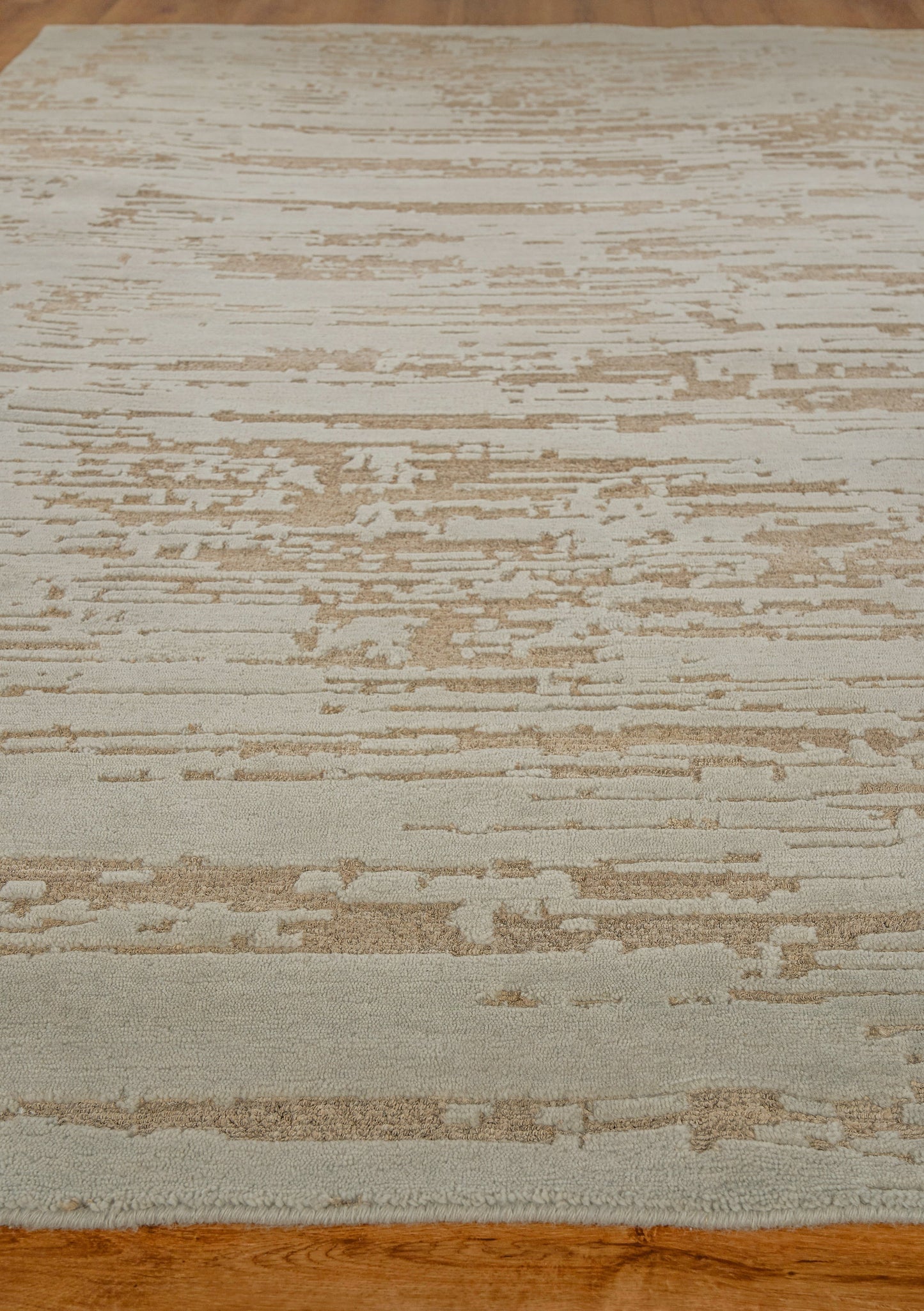 Rectangular beige and cream abstract rug with tan streaks on a wooden floor.