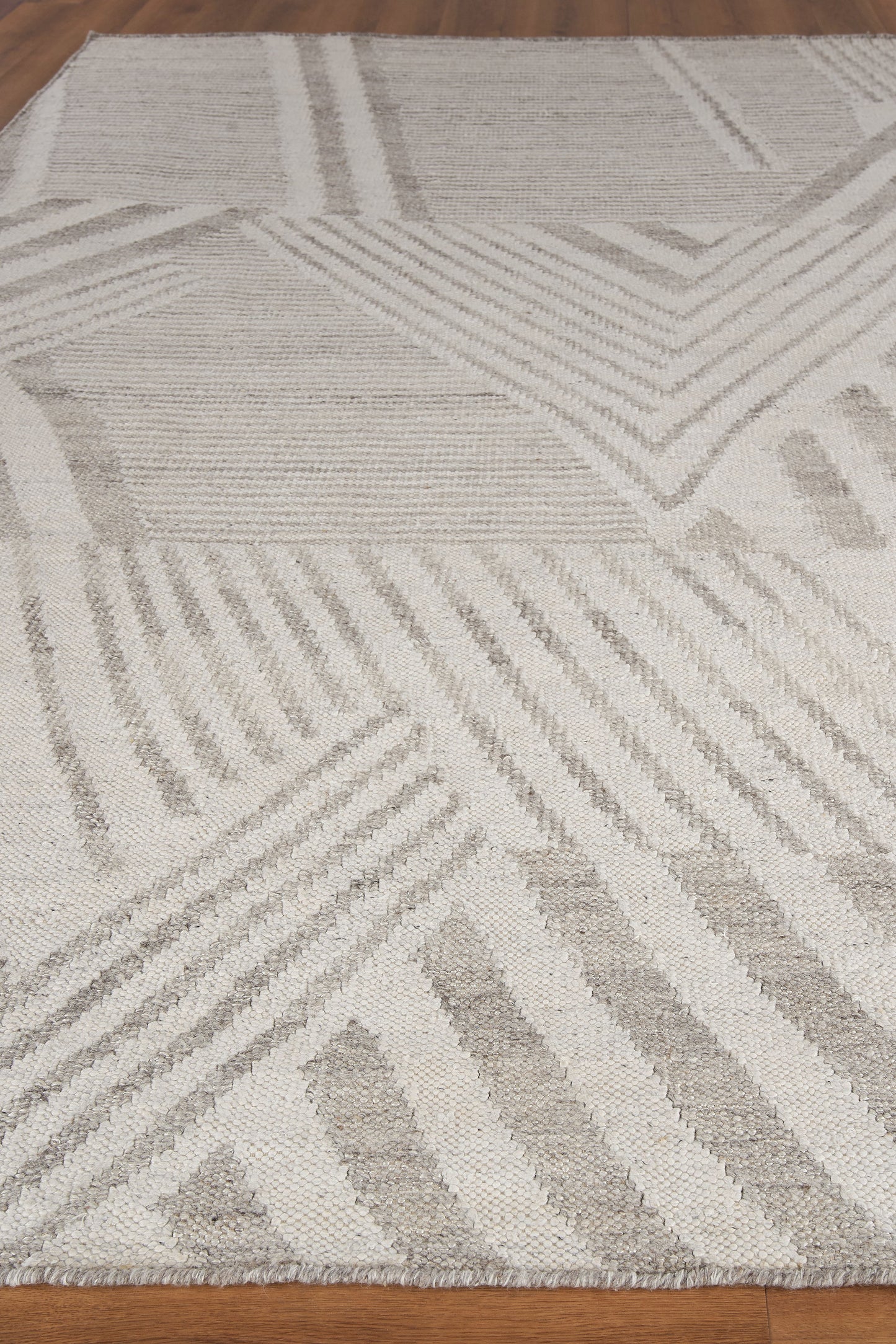 Light gray and ivory geometric area rug with angled stripe patterns and a soft plush pile; modern living room decor.