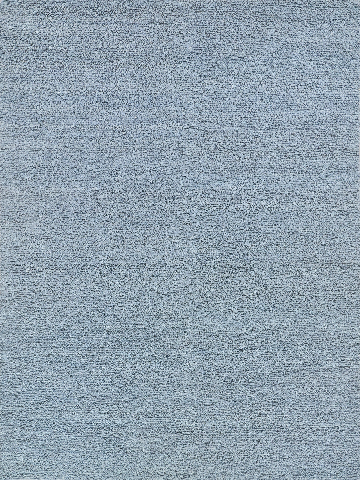 Close-up of a light blue, hand-loomed indoor rug with a soft, heathered weave.