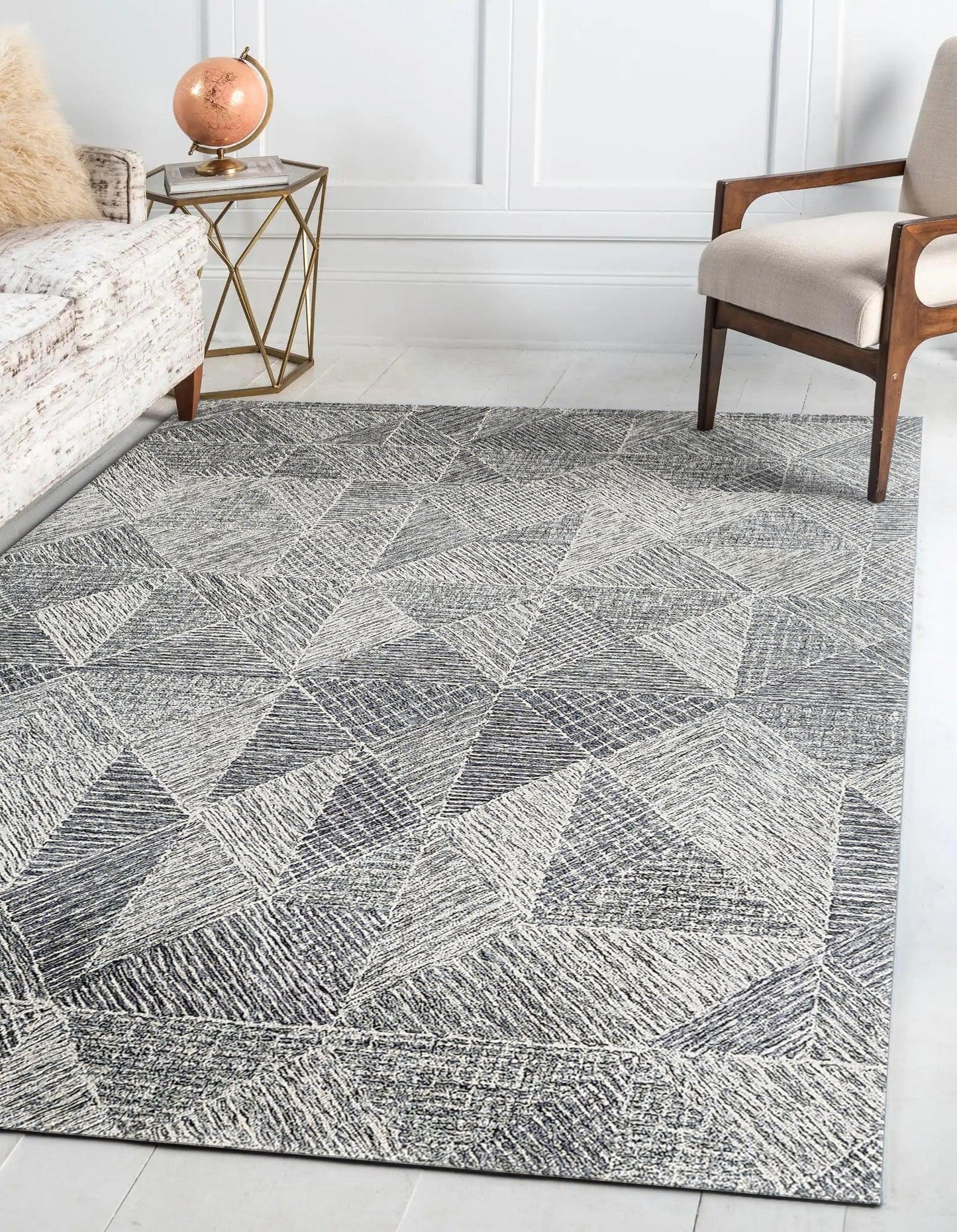Grey geometric area rug with diamond triangle pattern, woven texture in a modern living room with a beige sofa.