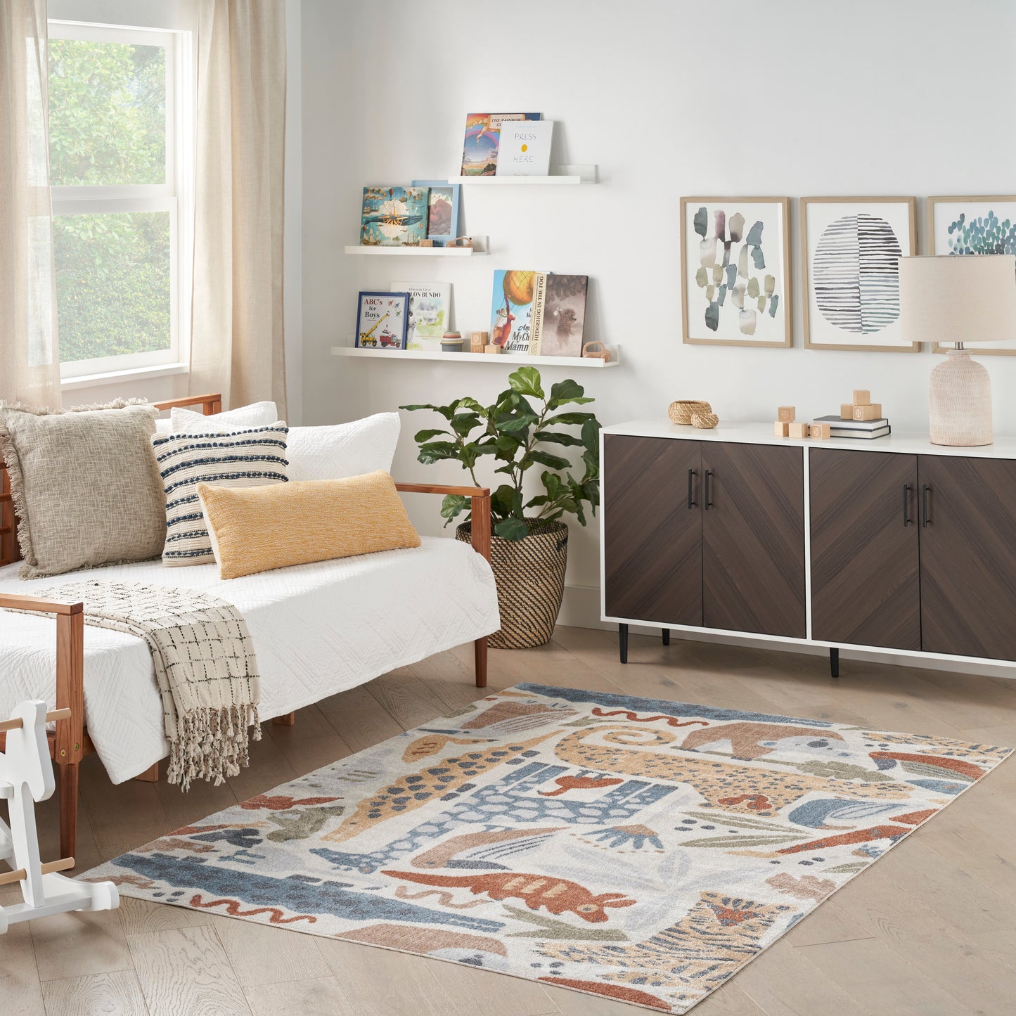 Rectangular woven area rug with abstract orange, blue and beige patterns in a bright living room.