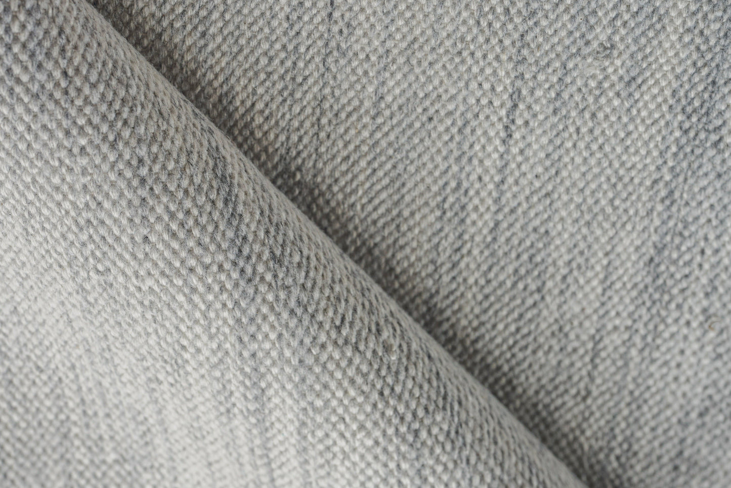 Close-up of light gray denim-like twill rug with visible diagonal weave and soft folds.