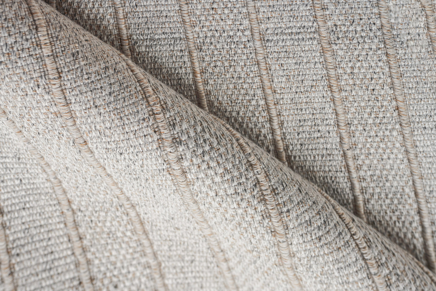 Beige indoor/outdoor flat-weave rug close-up with a ribbed texture and soft folds.