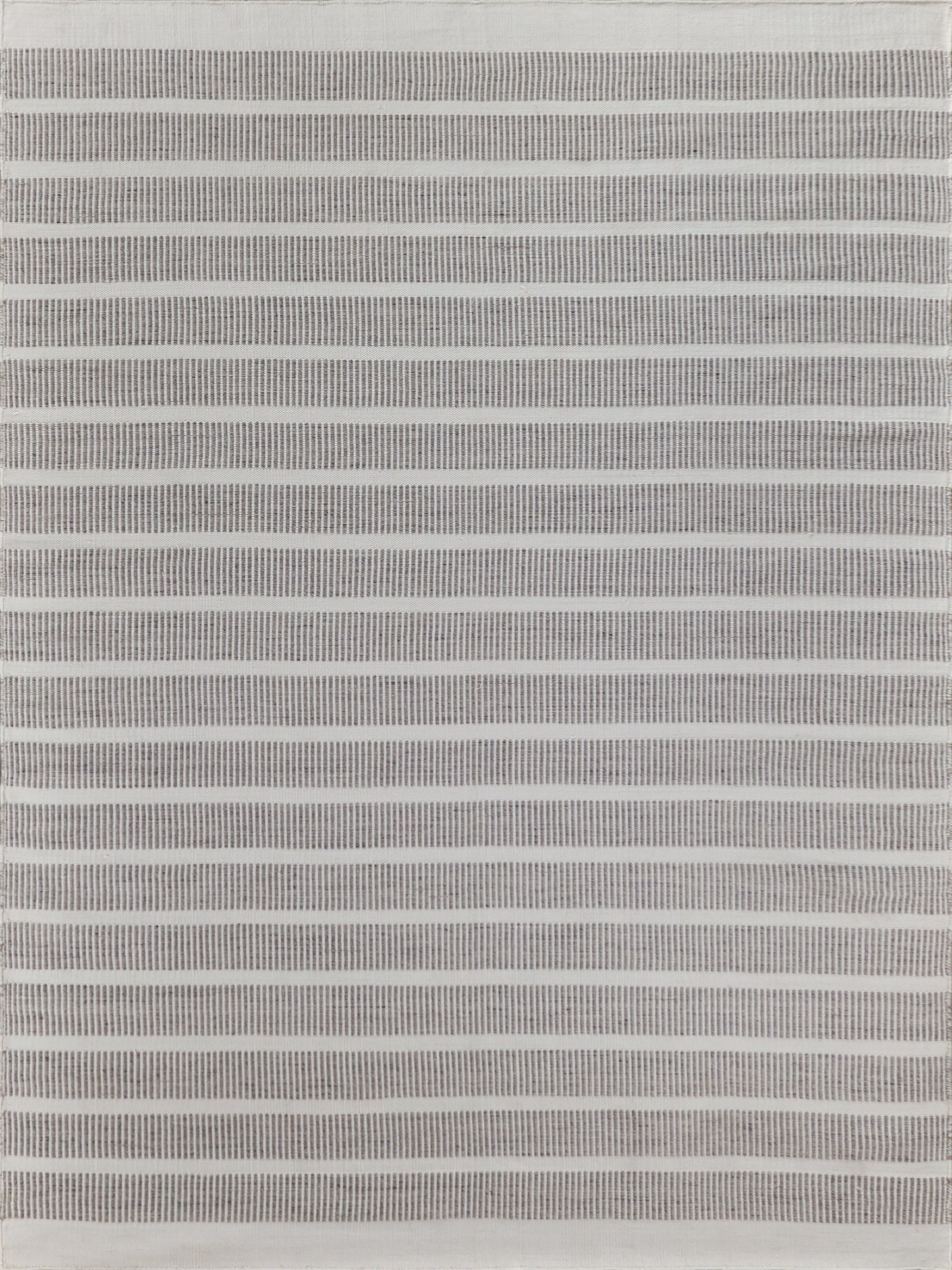 Textured flatweave rug in an 8' x 10' rectangle with alternating thin grey and white stripes, adding a modern touch.