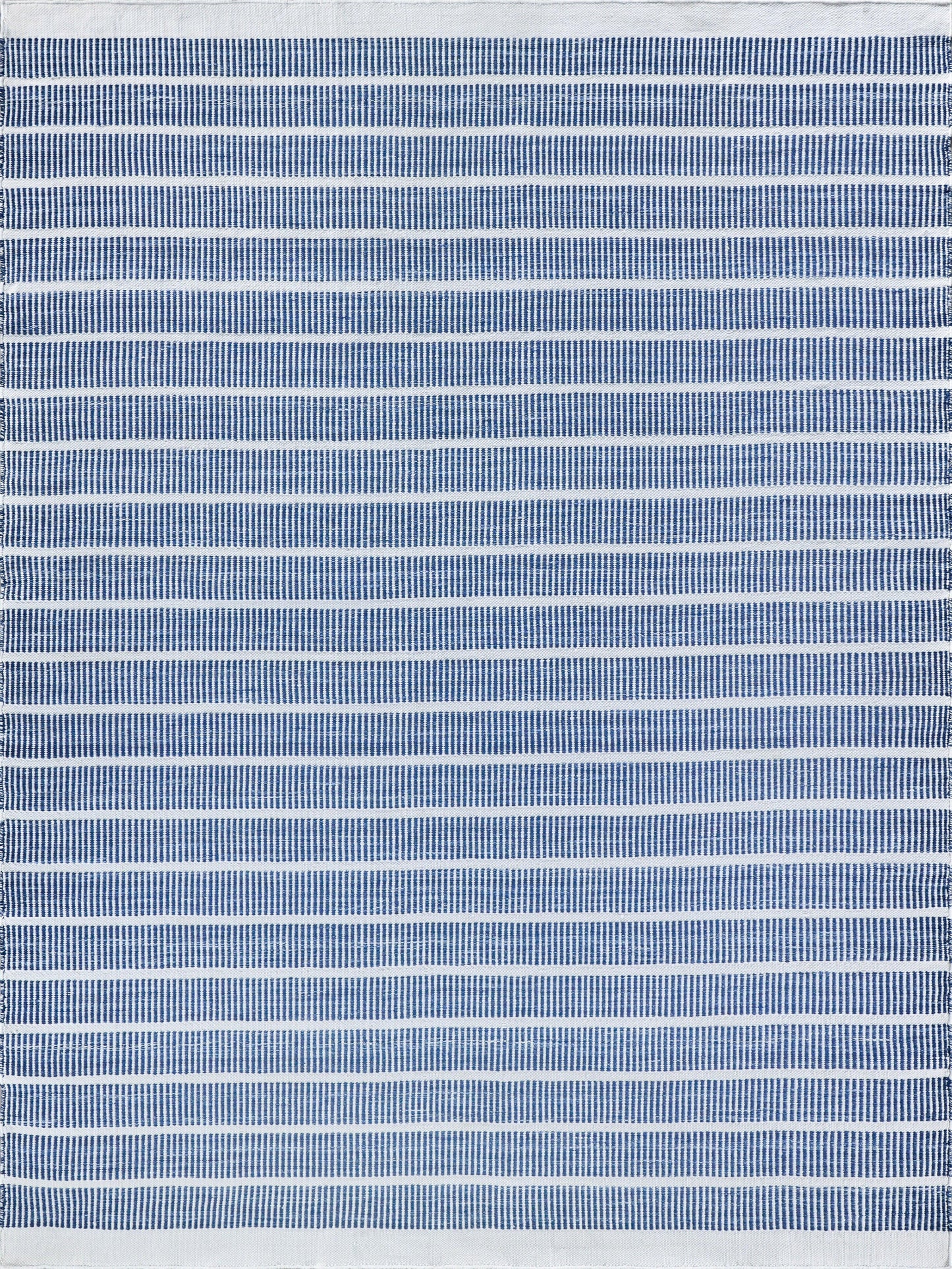 Navy blue and white striped flatweave rug with alternating bold and thin stripes.