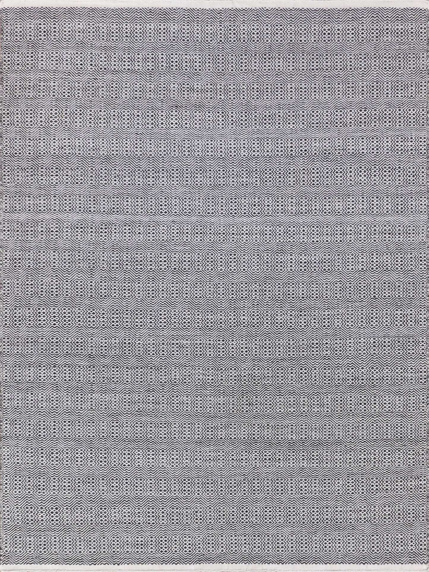 Textured woven rug featuring a monochrome pattern of alternating lines and shapes in black and white. Durable and stylish.