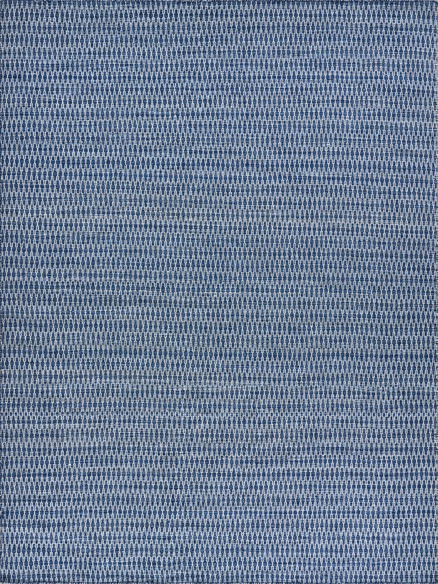Flatweave rug in blue tones with a geometric diamond pattern.