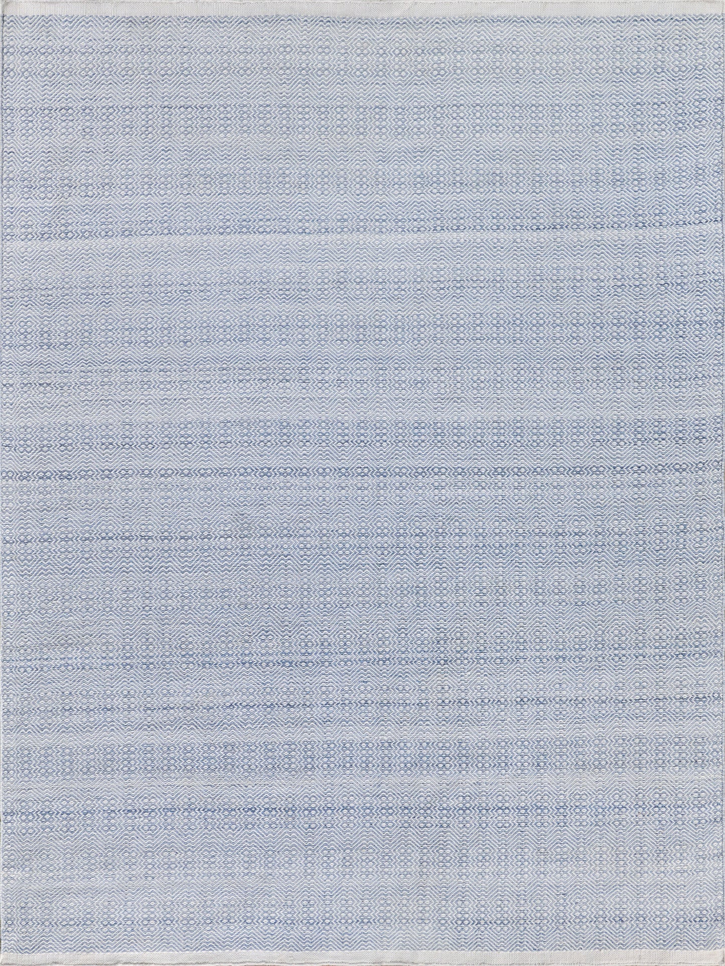 Blue rectangular flatweave rug with a subtle zigzag pattern and varying light and dark blue tones.