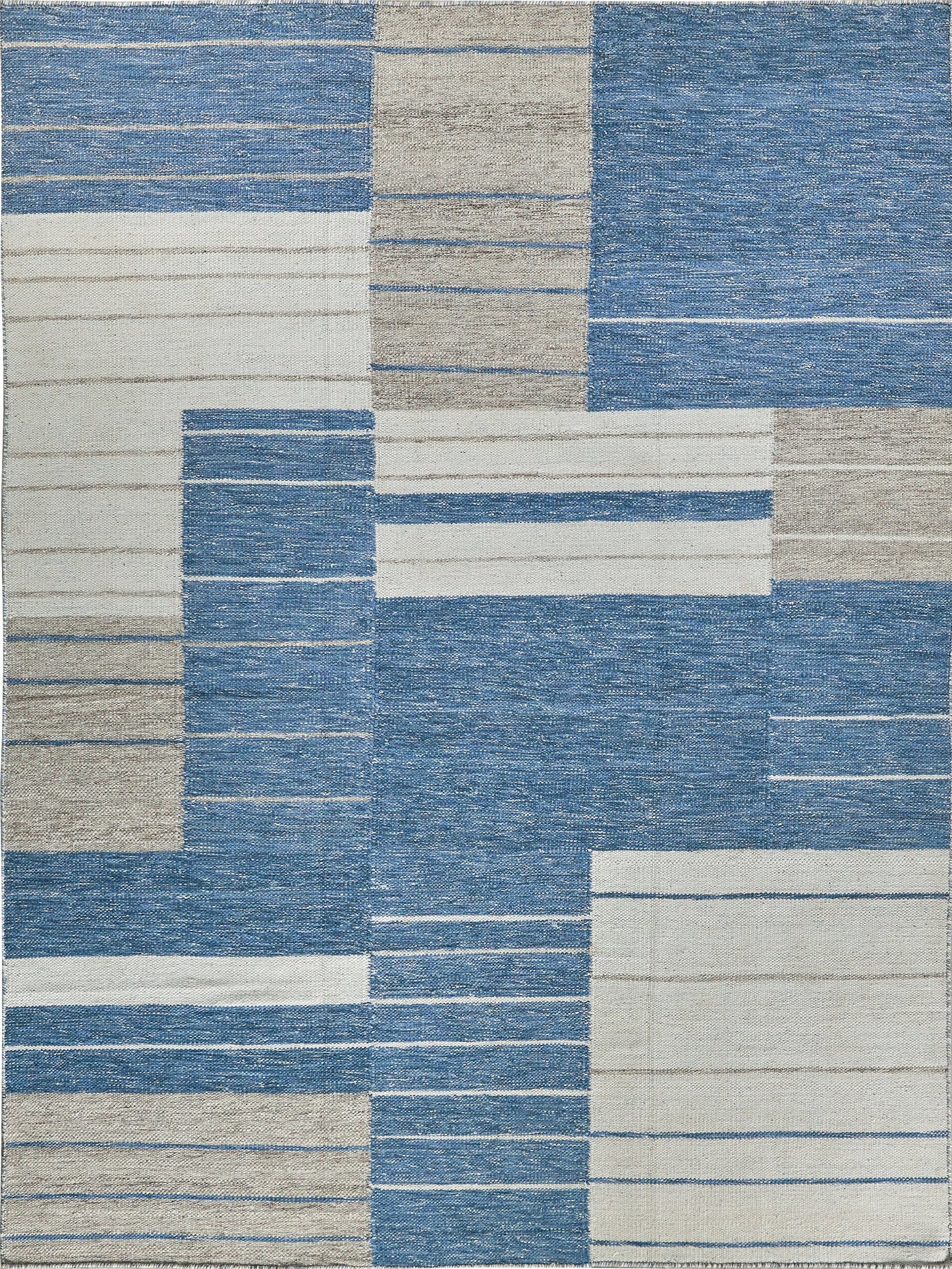 Abstract patchwork area rug in blue & beige with horizontal stripe blocks; modern geometric design.