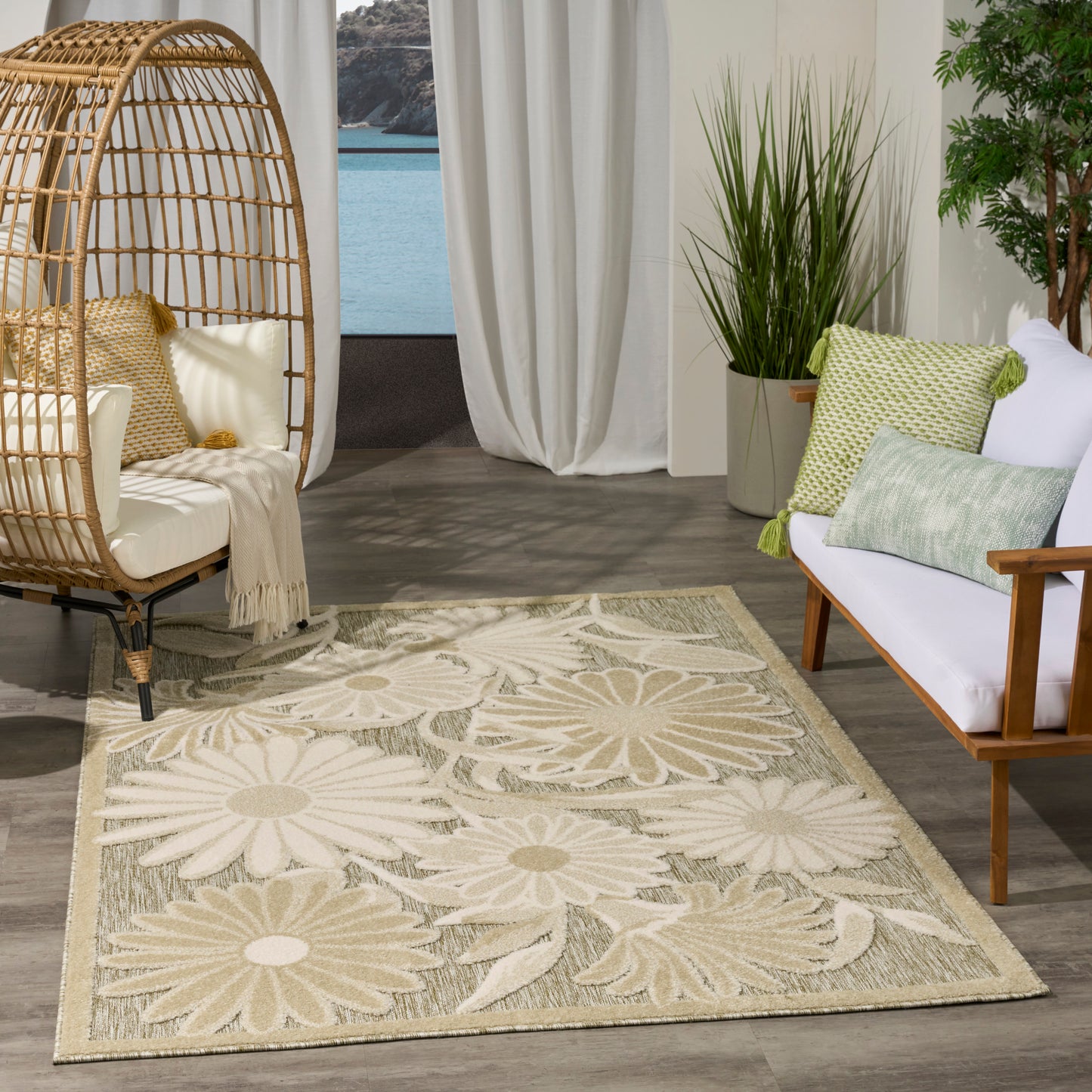 Beige floral area rug with large daisy motifs; wicker egg chair, white cushions, & potted greenery in a living room.