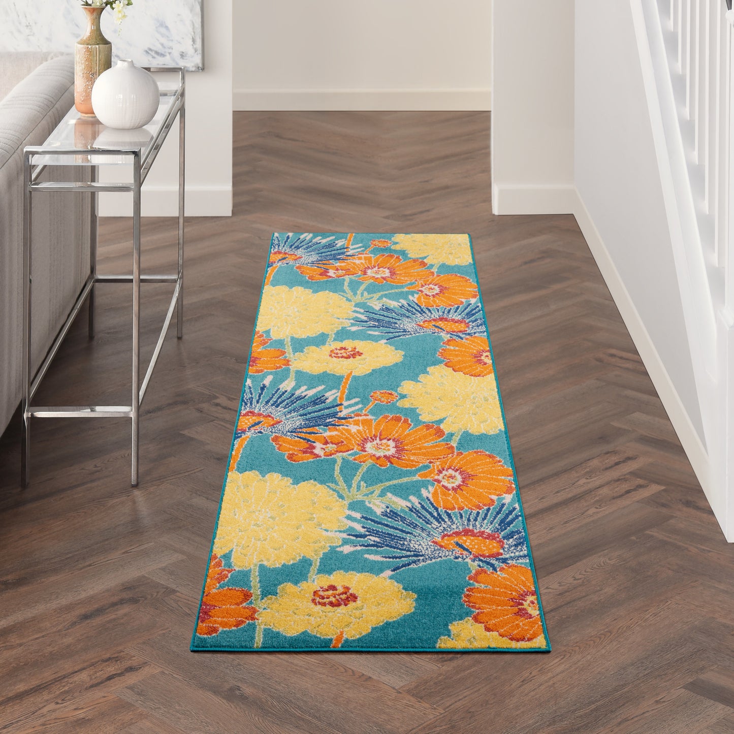 Long hallway runner rug with teal background and large yellow and orange tropical flowers; modern floral print.
