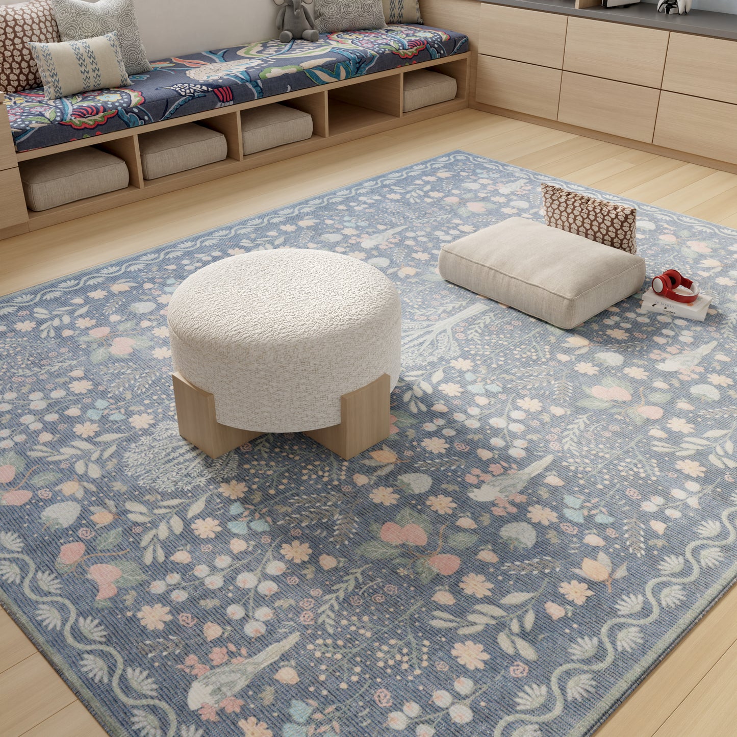 Cream boucle round ottoman with light wood legs on a blue floral area rug in a cozy living room.