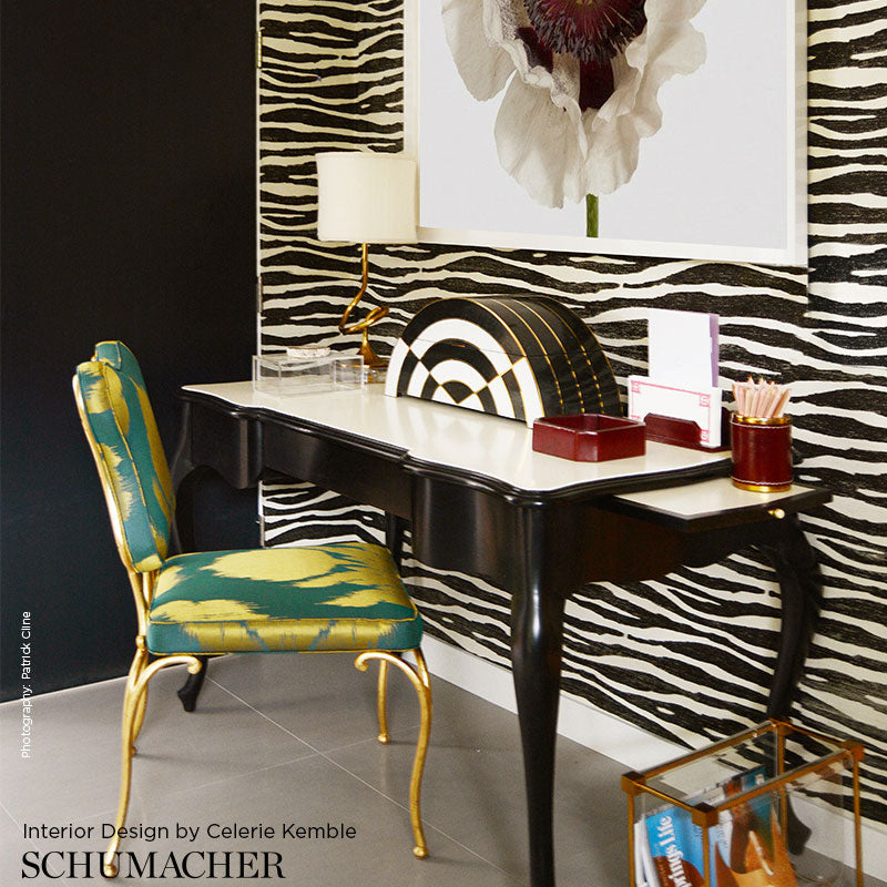 Vanity desk with zebra wallpaper, black curved legs, teal-gold chair, lamp, and bold black‑and‑white art.