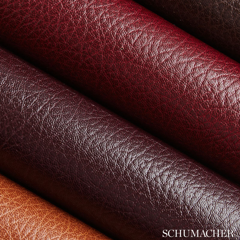 Coiled leather rolls in orange, tan, burgundy and red with a pebbled grain texture.