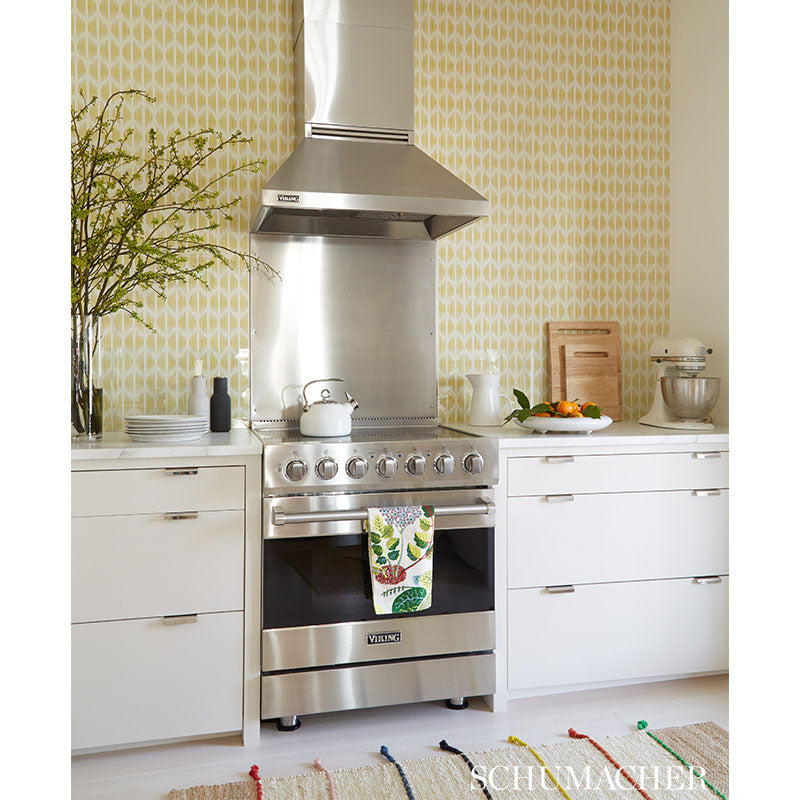 Stainless steel freestanding range with hood in white kitchen; yellow trellis wallpaper, towel, plant, mixer on counter.