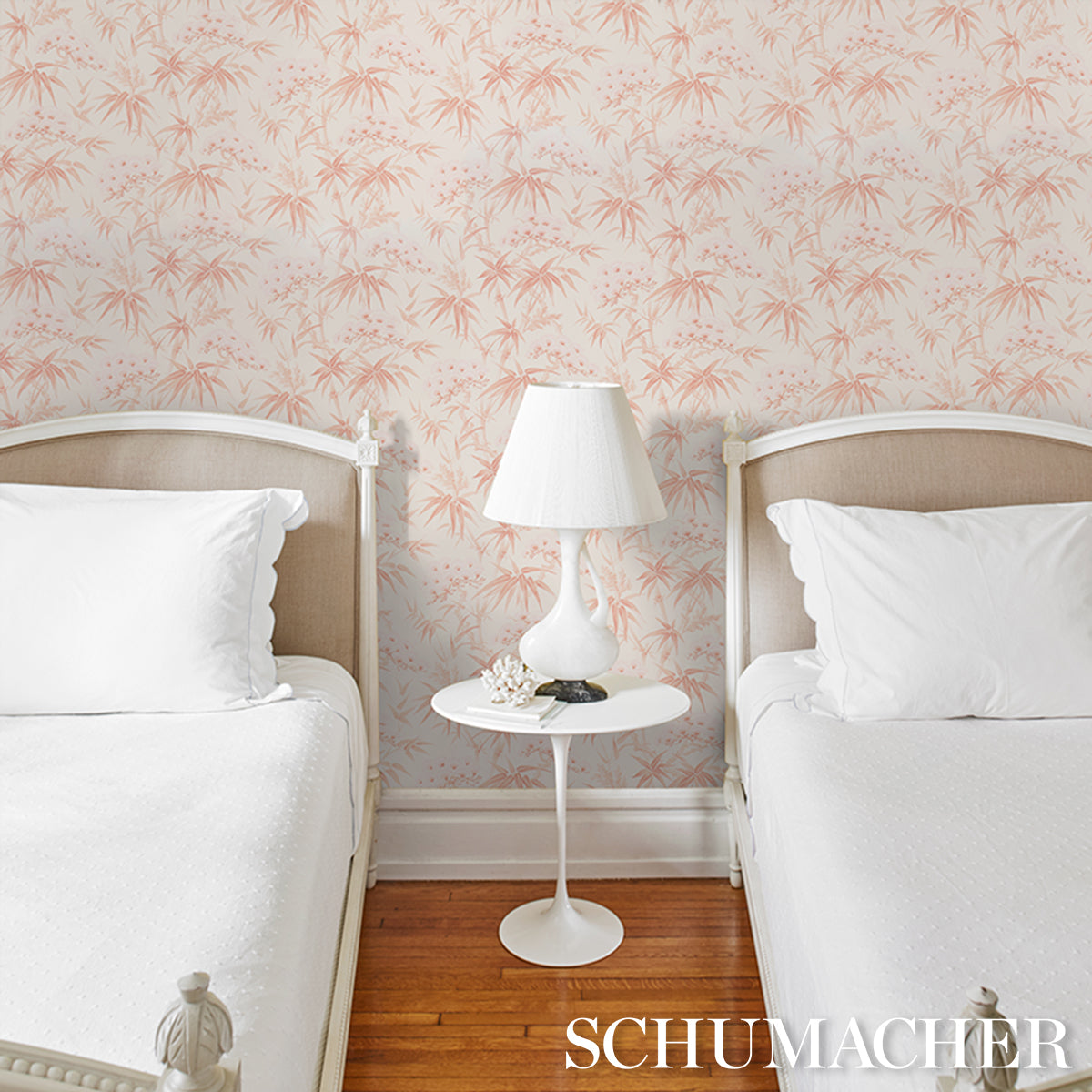 Twin bedroom with pink palm-pattern wallpaper, white bed frames, white bedding, and a white bedside table with a lamp.