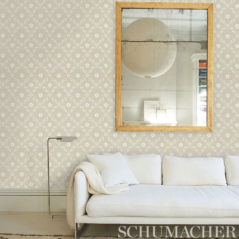Cream sofa with throw, slender floor lamp, beige patterned wallpaper, and a gold-framed wall mirror.