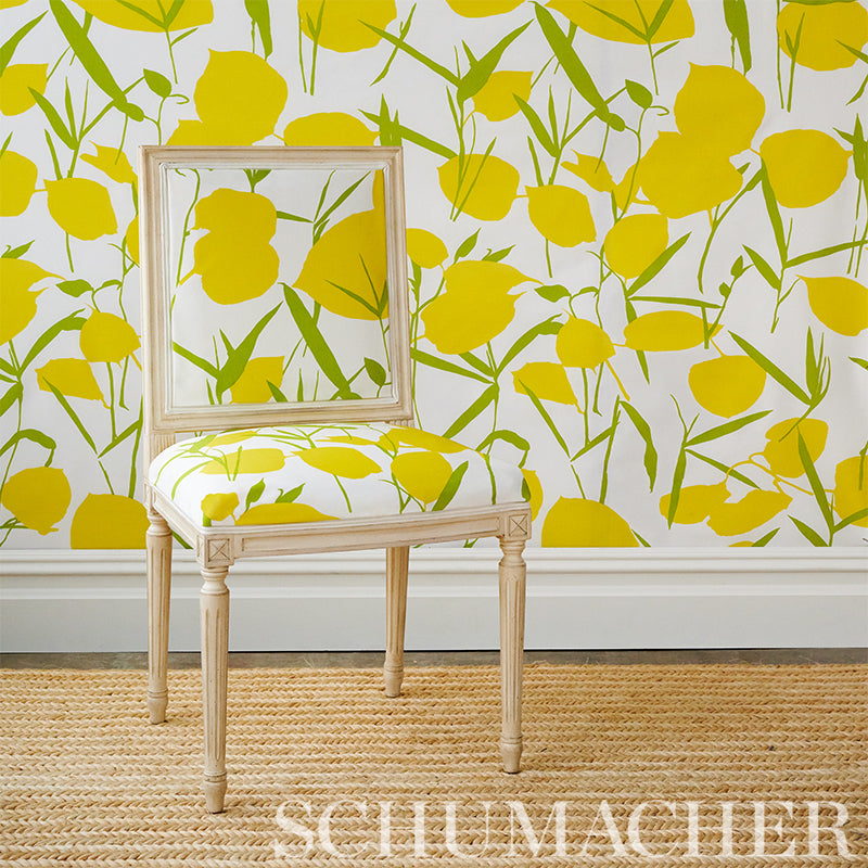 Light wood chair with square back, white upholstery, yellow floral pattern, set against bright yellow wallpaper.