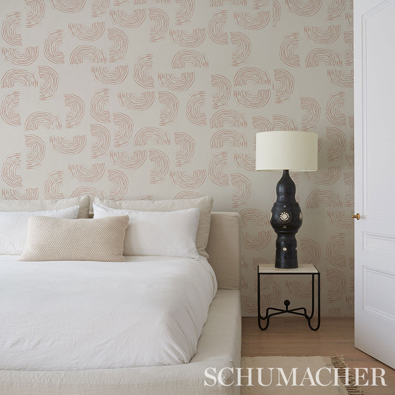 Coral on ivory wallpaper with a beige swirl pattern; white bedding with beige pillows and a black ornate lamp on a small metal-framed nightstand.