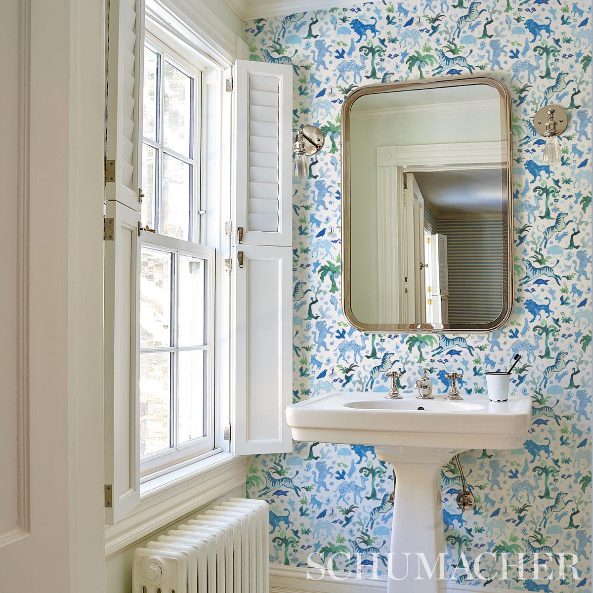 Schumacher Happy Menocal Beasts Wallpaper in blue and green featuring whimsical hand-painted animals and floral motifs in a playful carnival-inspired design. Artistic designer wallpaper with rich tonal variation and mid-scale pattern ideal for statement walls in living rooms, bedrooms, dining rooms, powder rooms, and creative interior spaces.