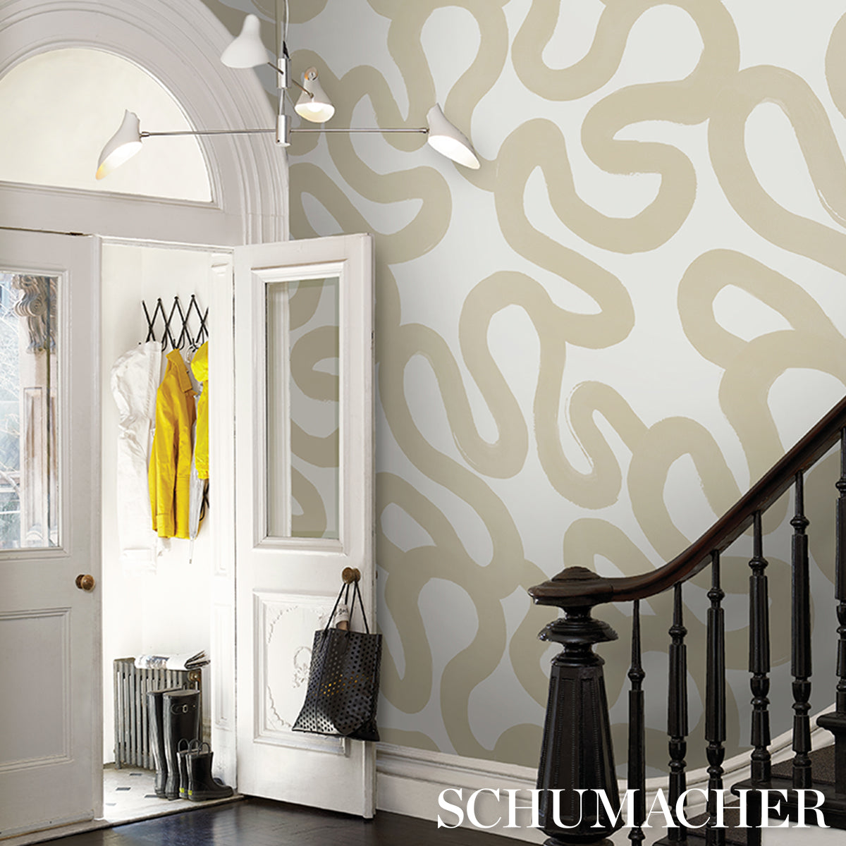 Bright entryway with white double doors, beige abstract wallpaper, dark wood staircase, yellow coat on hook and black tote.