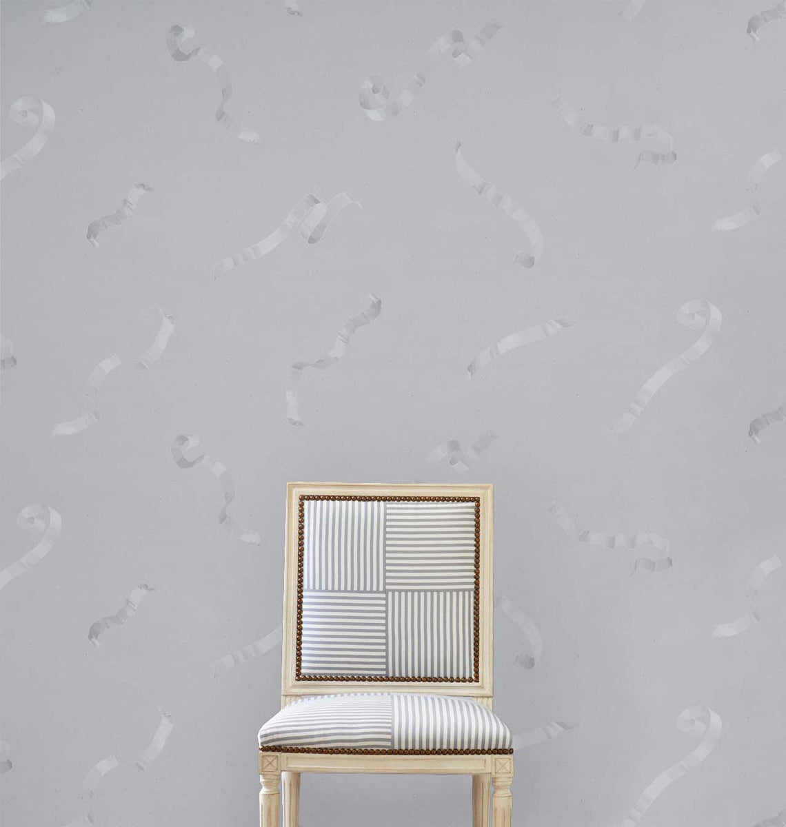 Grey upholstered chair with a patchwork striped back, cushioned seat, and gold trim.