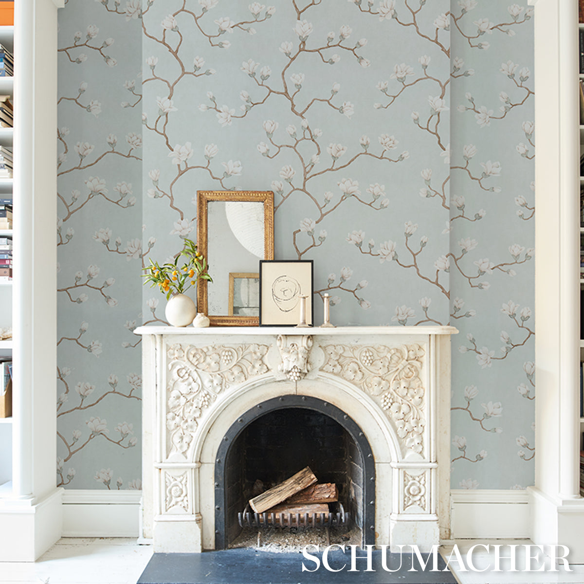 Blue floral wallpaper with magnolia tree motif in dusty sky tones.