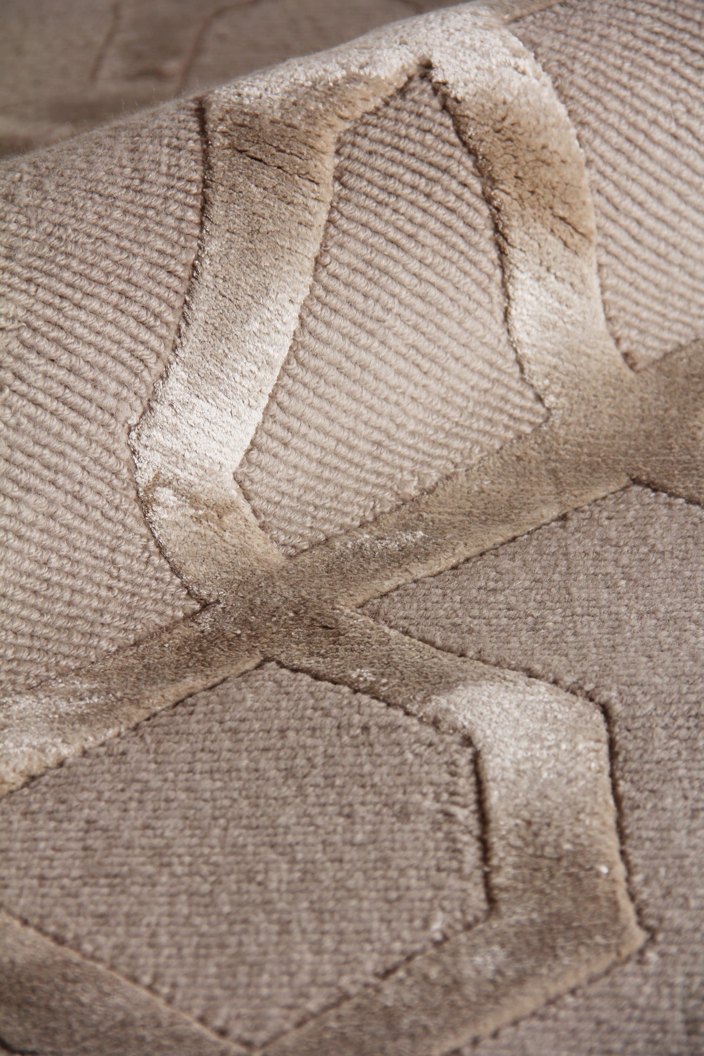 Beige velvet-textured rug with a subtle geometric pattern; close-up of the hand-knotted weave.