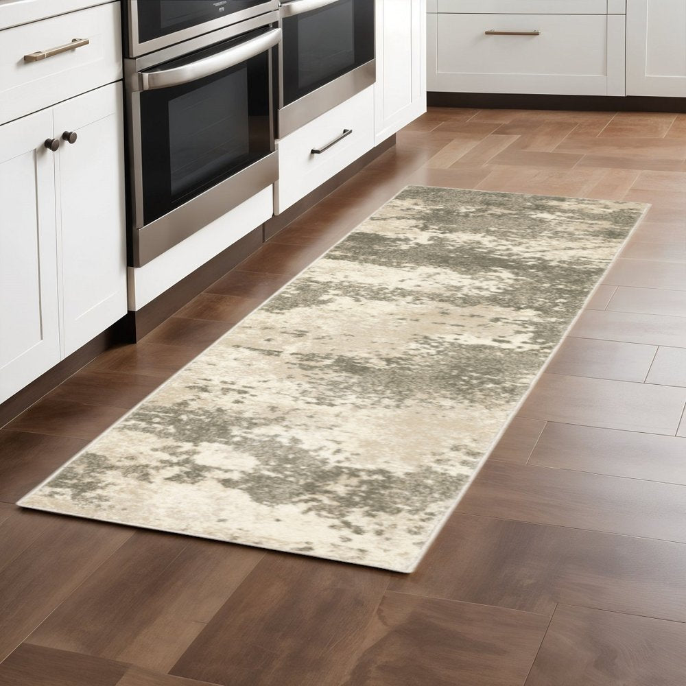 Long beige-gray abstract rug runner on brown wood floor in a white kitchen with stainless steel ovens.
