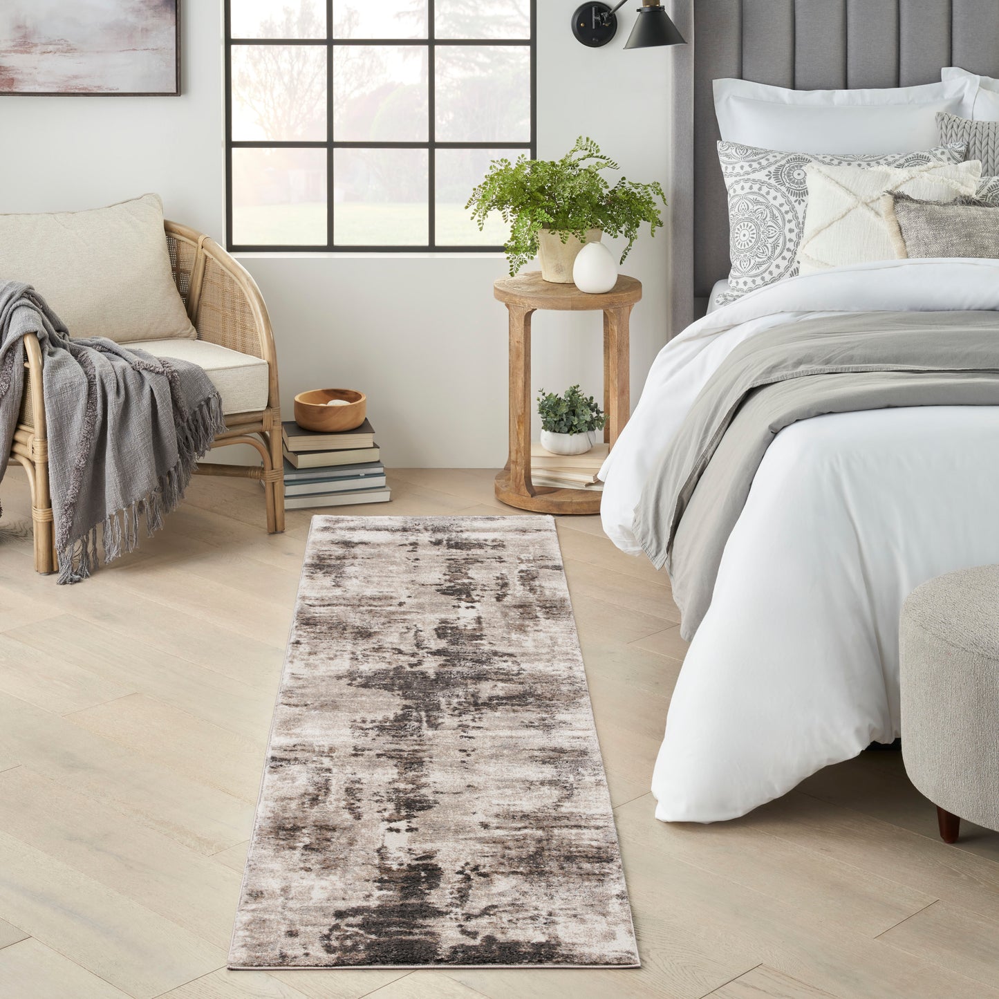 Long neutral runner rug with a distressed abstract pattern in beige, taupe and charcoal beside a bed in a modern bedroom.