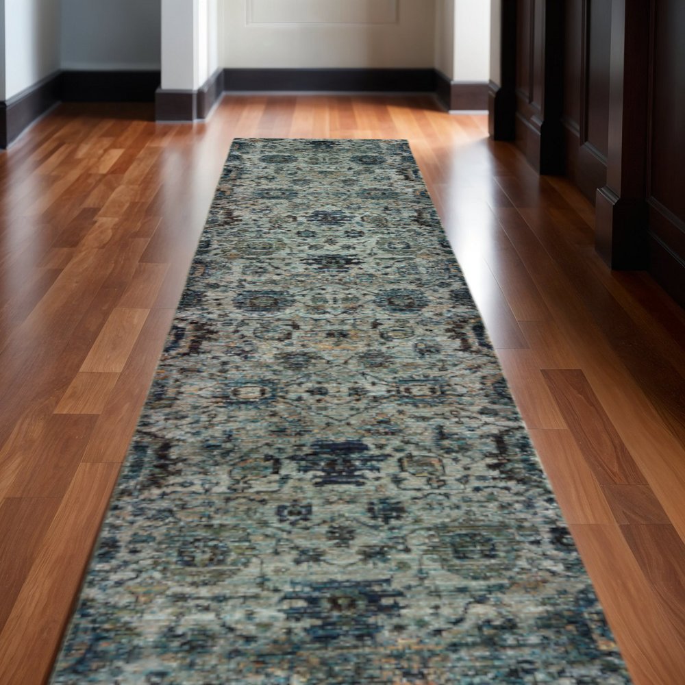 Long oriental-style runner rug in blue, beige and black running down a hardwood hallway.