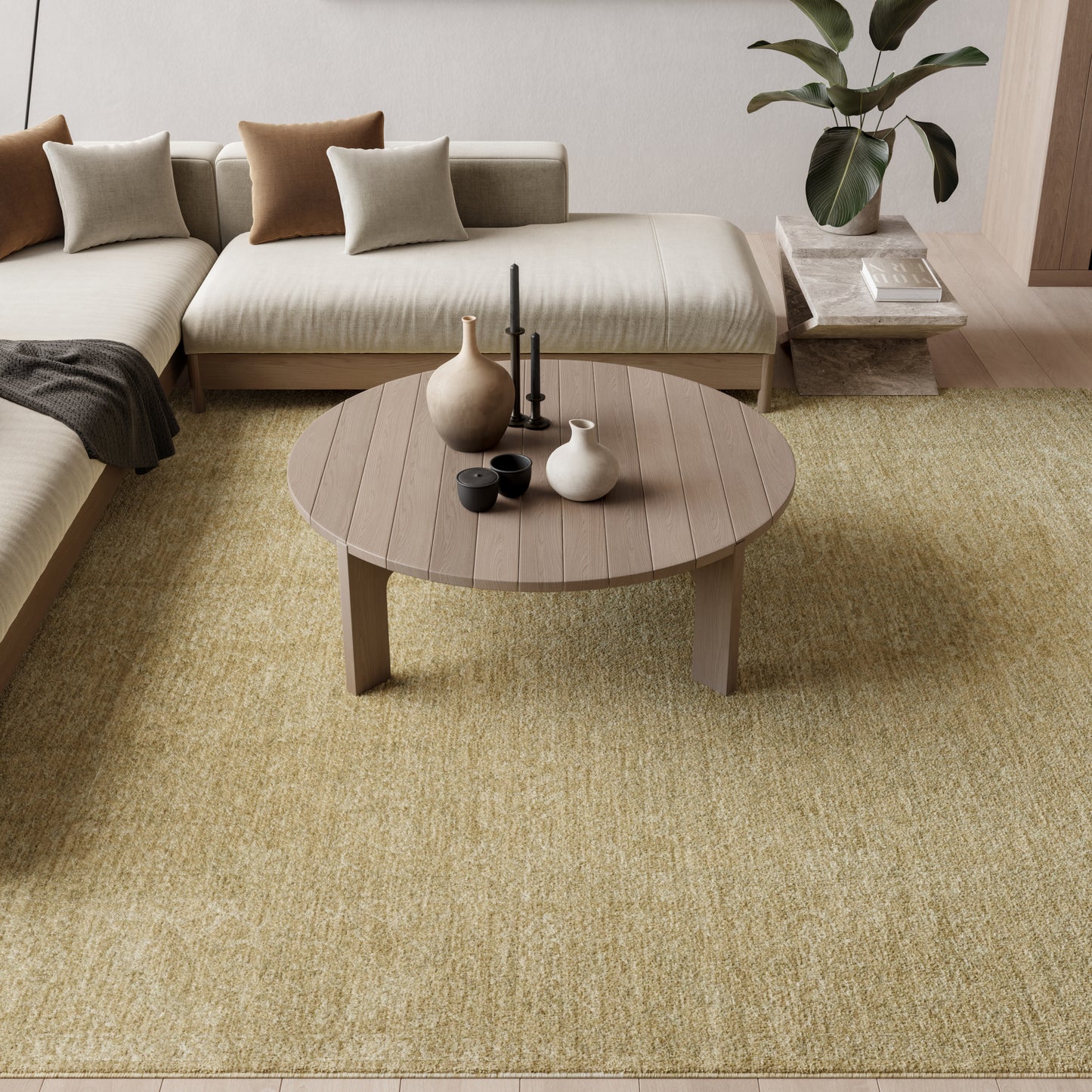 Round wooden coffee table on a yellow-beige rug, beige sectional with brown & taupe cushions, ceramic vases & candles.