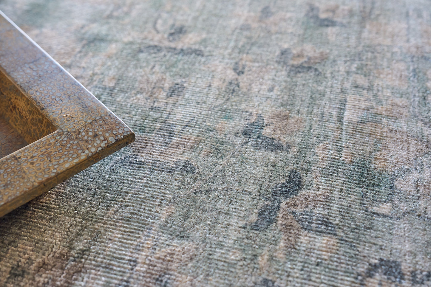 Rectangular rug with an embossed crocodile-skin pattern in bronze-brown, 6' x 9', laid on a muted green and beige surface.