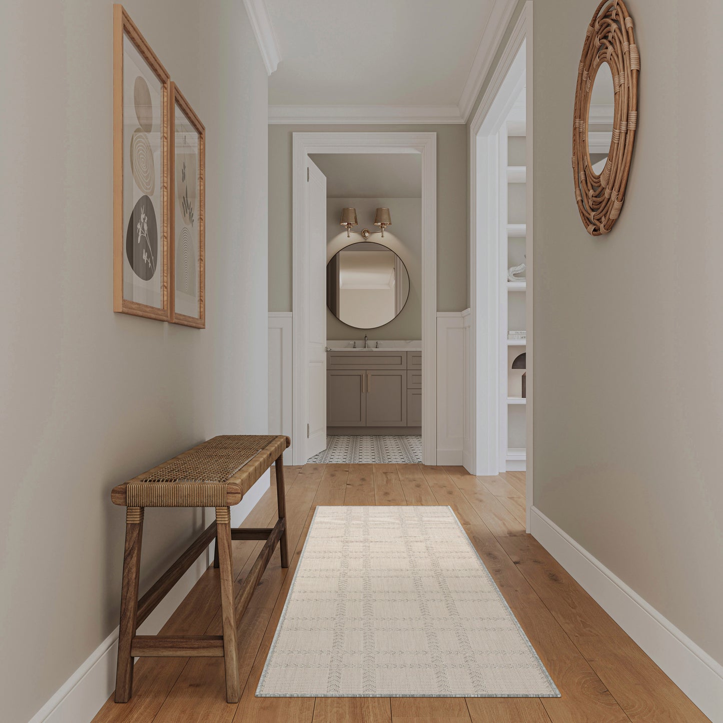 Neutral hallway with wooden floor, woven bench, cream rug runner, framed art, and wicker round mirror; bathroom ahead.