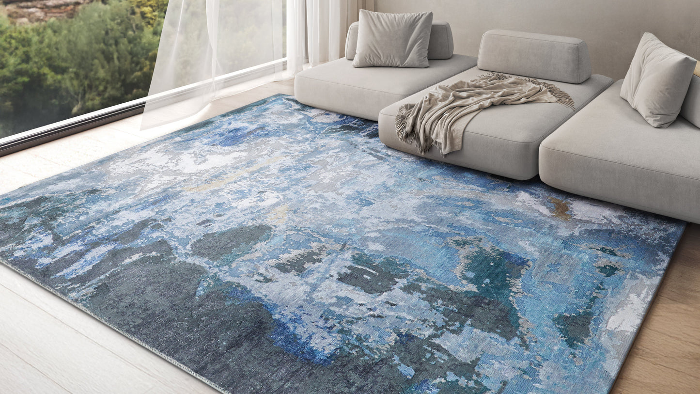Abstract blue-gray area rug in a modern gray sectional living room with a tan throw blanket.