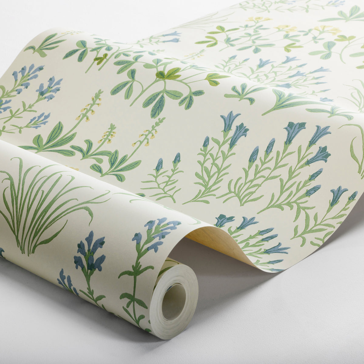 Cream wallpaper roll with green and blue leaf motifs; lavender-toned florals on a soft background.