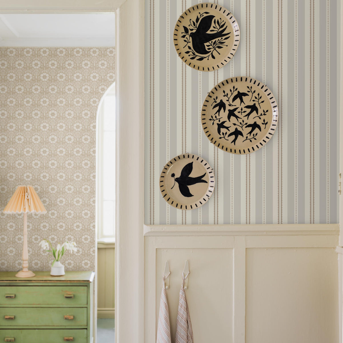 Three beige circular wall plates with black bird silhouettes and cutout rims on striped wallpaper.