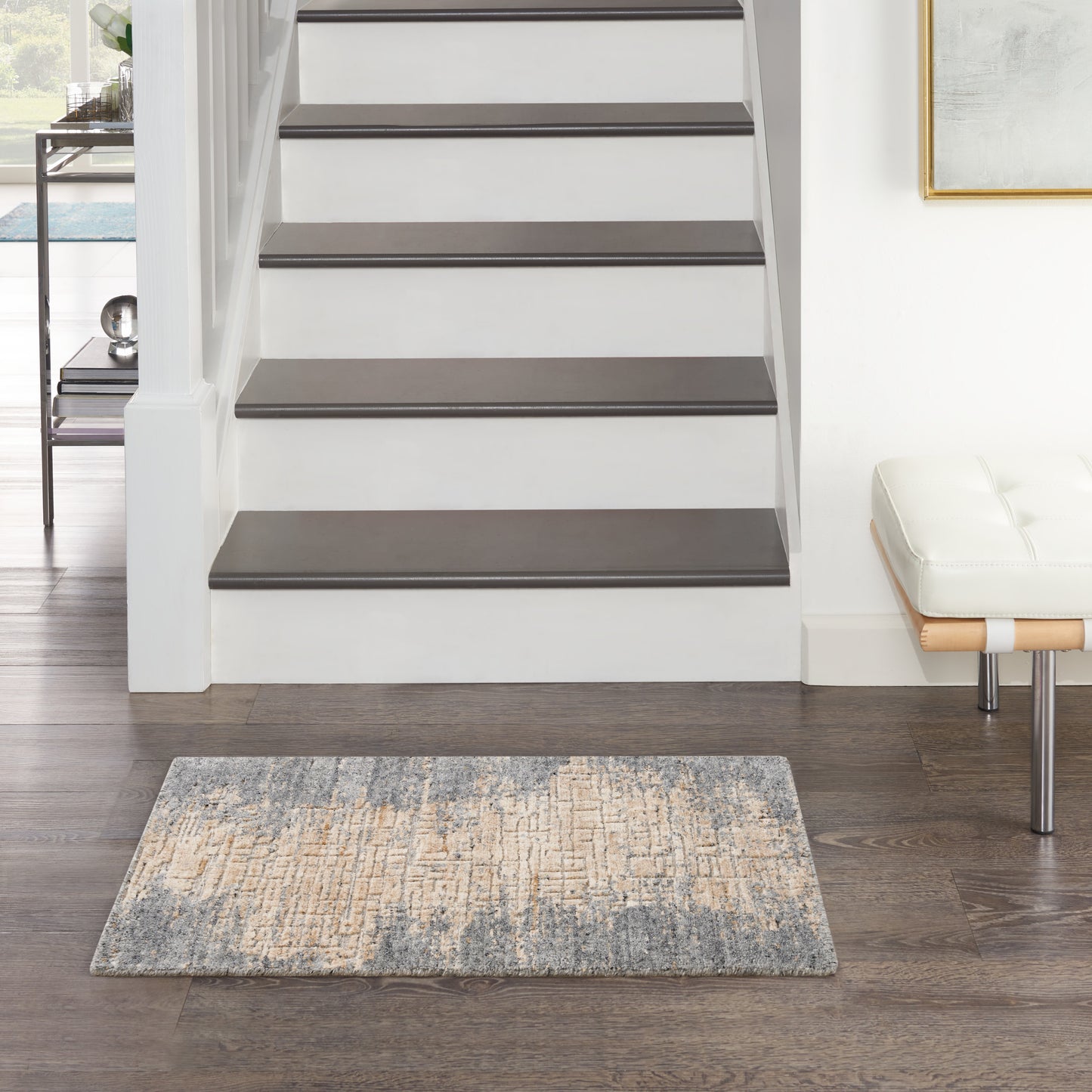 Modern entryway rug (2' x 3') with a light textured surface on dark flooring, paired with a white tufted bench.