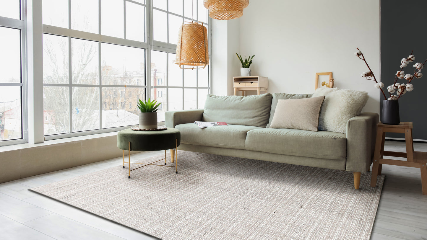Modern living room with large windows, beige sofa, light rug, round dark coffee table, wicker pendant lights, plants.