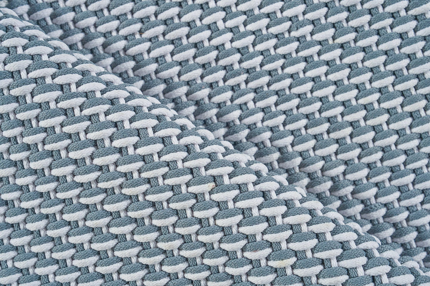 Close-up of teal & light gray woven rug with a chunky braided texture.