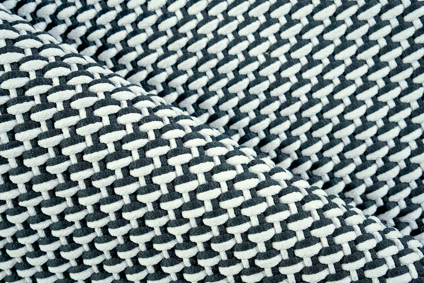 Dark navy and white hand-woven rug with a chunky, interlaced basket-weave pattern; indoor/outdoor use.