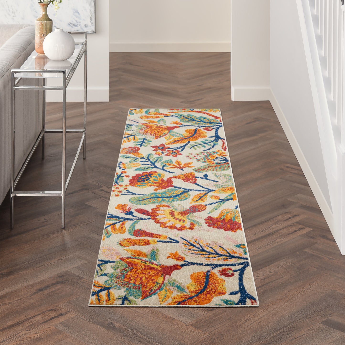 Colorful hallway runner with orange, blue & yellow floral birds on light background; wood chevron floor.