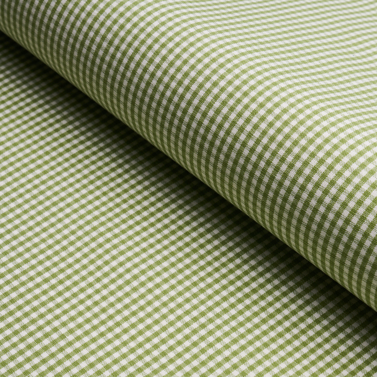 Green and white gingham cotton fabric rolled, close-up checkered weave.