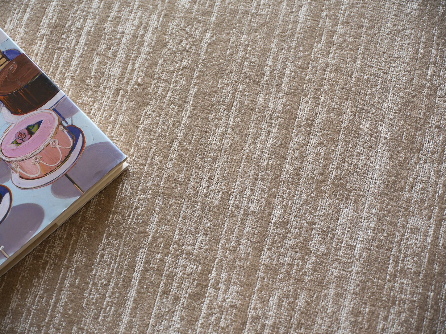 Open illustrated book with pink teacup artwork on pastel page, resting on beige striped carpet.