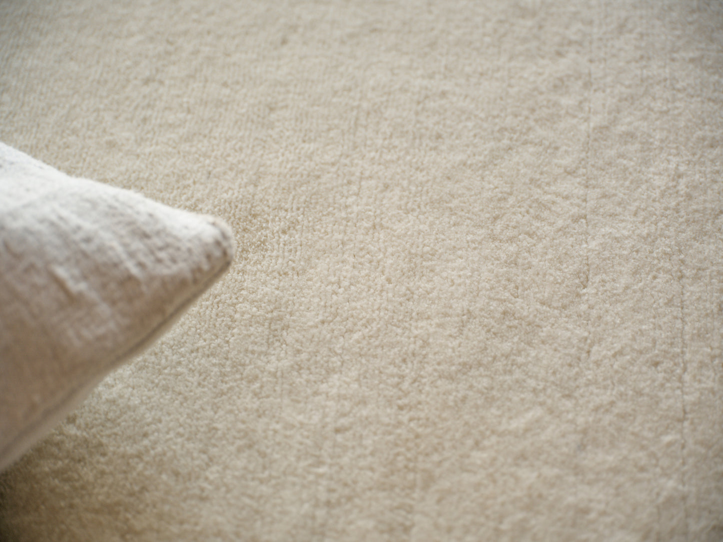 Cream rug with a soft woven texture on a beige background; minimalist, cozy home decor.