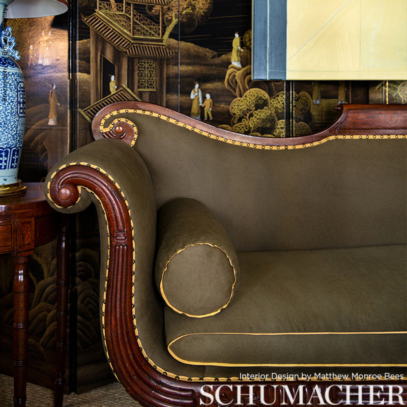 Olive green vintage sofa with curved mahogany frame, brass nailhead trim, matching cylindrical bolster; ornate room setting.